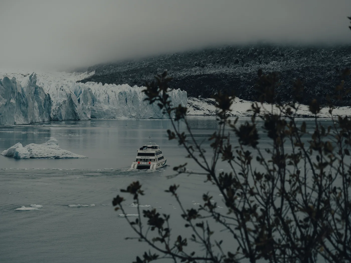 A small boat sailing close to a misty glacier ice front in Patagonia